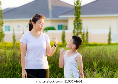 (Asian People) Mom And Cute Boy Are Clench One's Hand For Take Confidence Signal At Garden House.
