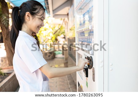 Asian people paying or buying hygienic drinking water from automatic vending machine in area lacking clean water,student inserting coin in to beverage vending machine,child girl choose for the drinks
