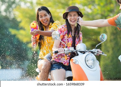 Asian people play songkran festival in the summer april They ride motorcycles. Then hit the powder