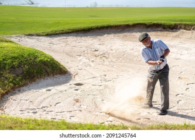 Asian People Senior Man Hitting Golf Ball From A Bunker On Golf Course To The Green. Healthy Elderly Male Golfer Enjoy Leisure Activity Outdoor Sport Golfing At Golf Country Club In Summer Vacation