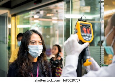 Asiatische Menschen, die auf eine Körpertemperaturkontrolle warten, bevor sie durch Thermoscan oder Infrarot-Wärmekamera Zugang zu Gebäuden gegen Epidemie-Grippe-Covid19 oder Corona-Virus von Wan im Amt haben