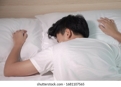 Asian person wearing a white T-shirt is sleeping in bed after working hard from work.