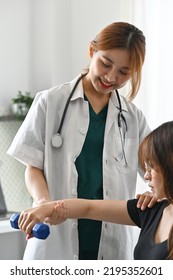 Asian Physiotherapist Working With Female Patient By Using Dumbbell In Clinic 