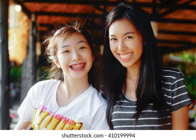 Asian Playful Younger Sister And Older Sister Smiling Happily