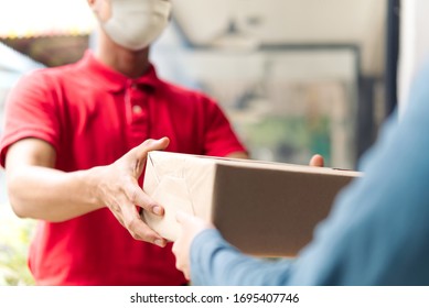 Asian postman, deliveryman wearing mask carry small box deliver to customer in front of door at home. Man wearing mask prevent covid19, corana virus affection outbreak. Social distancing work concept.