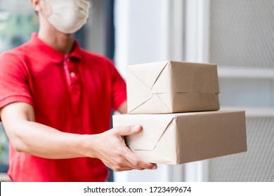 Asian Postman, Deliveryman Wearing Mask Carry Small Box Deliver To Customer In Front Of Door At Home. Man Wearing Mask Prevent Covid19, Corana Virus Affection Outbreak. Home Delivery Shopping Concept.