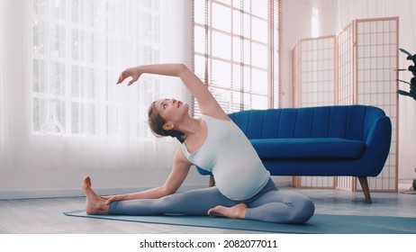 Asian Pregnant Woman Doing Yoga Exercises At Home.