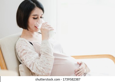 Asian Pregnant Woman Drinking A Glass Of Milk. Mom And Kids, Mother Healthy And  Newborn Preparation Concept. 
