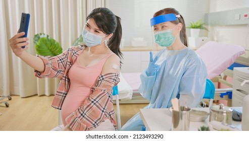 Asian Pregnant Woman And Female Doctor Wearing Face Mask Take Selfie By Mobile Phone After Receiving Coronavirus Vaccine