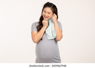 Asian Pregnant Woman Holding Baby Cloth For Baby Newborn Isolated On White Background.Pregnant Woman Packing Baby Stuff Ready For The Maternity Hospital.Pregnancy Prepare For Newborn Concept