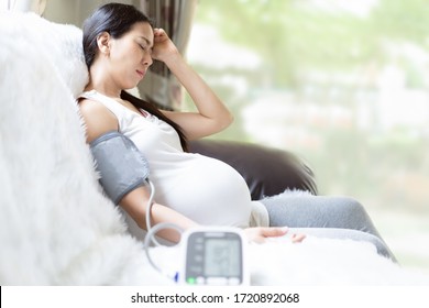 Asian Pregnant Woman Is Monitor Blood Pressure While She Has Headache To Prevent Hypertension During Pregnancy Period, Concept Of Healthcare, Sickness And Health Concern In High Risk Group Pregnancy.