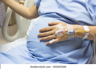 Asian Pregnant Woman patient is on drip receiving a saline solution on bed VIP room at hospital, selective focus.
