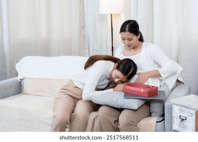 Asian pregnant woman sitting on a sofa with a friend resting her head on the baby bump. Expressing affection and care. Calm and peaceful atmosphere, close bond between friends. Pregnancy anticipation. - Powered by Shutterstock