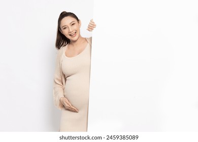 Asian pregnant woman is standing behind the white blank banner and pointing to empty copy space advertisement board on red background, Looking at camera - Powered by Shutterstock