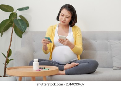 Asian Pregnant Woman Using Mobile Phone Searching Information And Reading Medicine Label And Prescription Medications