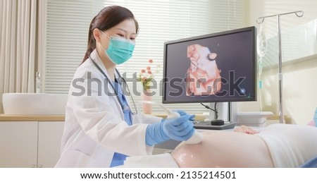 asian pregnant woman wearing protective face mask to prevent COVID19 has uterus utltrasonographic diagnosis - female doctor uses 3D three dimensional ultrasound to scan baby