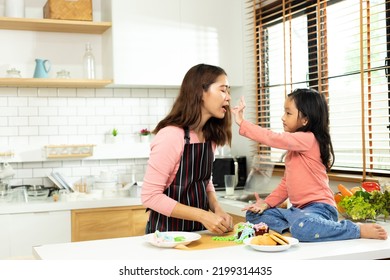 Asian Preschool Kid Person Make Cake Cooking In Kitchen, Mother Prepare Decoration Pretty With Fun Educate On Cupcake For Birthday Sister. Cream Mess All Over Hair Face Mouth, Feel Happy, Copy Space