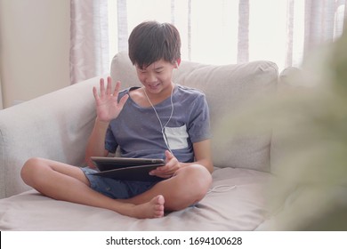 Asian preteen boy making facetime video calling with tablet at home, using zoom, google meet, facebook room learning online app, social distancing, homeschooling, learning remotely, new normal concept - Shutterstock ID 1694100628