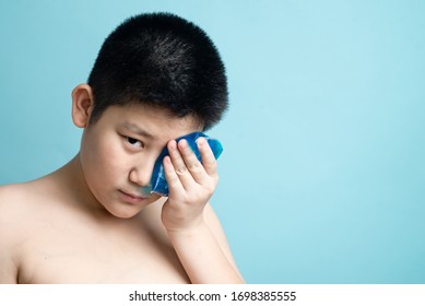 Asian Preteen Boy Using Cold Compress Gel On Bruises Face On Blue Background.