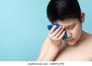 Asian Preteen Boy Using Cold Compress Gel On Bruises Face On Blue Background.