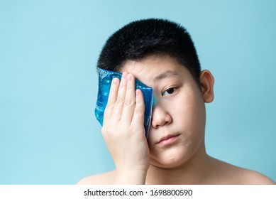 Asian Preteen Boy Using Cold Compress Gel On Bruises Face On Blue Background.