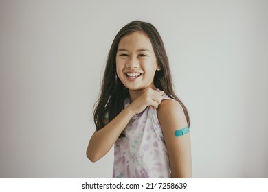 Asian Preteen Girl Showing Her Arm With Bandage After Got Vaccinated Or Inoculation, Child Immunization, Covid Vaccine Concept