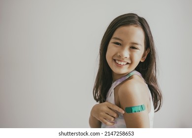 Asian Preteen Girl Showing Her Arm With Bandage After Got Vaccinated Or Inoculation, Child Immunization, Covid  Vaccine Concept