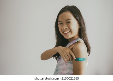 Asian Preteen Girl Showing Her Arm With Bandage After Got Vaccinated Or Inoculation, Child Immunization, Covid  Vaccine Concept