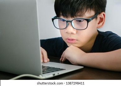An asian preteen (tween) boy wearing Blue Light Blocking Glasses while coding with his laptop to protect his eyes from eyes problem. Computer Vision Syndrome: KIDS health, dry eyes concern - Close up