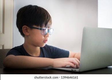 An Asian Pre-teen (tween) Boy Wearing Blue Light Blocking Glasses While Coding With His Laptop To Protect His Eyes From Eyes Problem. Computer Vision Syndrome: KIDS Health, Dry Eyes Concern.