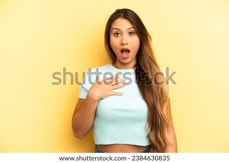 asian pretty woman feeling shocked, astonished and surprised, with hand on chest and open mouth, saying who, me?