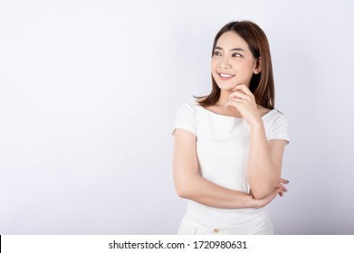 Asian pretty woman in white t-shirt and white pants pretending glad happy face with copy space on white background. Information telling, shopping promotion, announcement, selling support concept.
