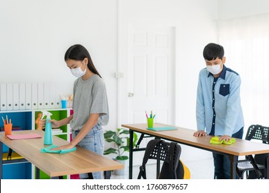 Asian Primary Student Wearing Masks To Prevent The Outbreak Of Covid 19 In Classroom And Cleaning Table By Wipe And Alohol Spray To Eliminate The Chances Of Contamination COVID-19.