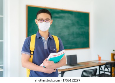 Asian Primary Students Boy With Backpack And Books Wearing Masks To Prevent The Outbreak Of Covid 19 In Classroom While Back To School Reopen Their School, New Normal For Education Concept.
