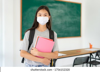 Asian Primary Students Girl With Backpack And Books Wearing Masks To Prevent The Outbreak Of Covid 19 In Classroom While Back To School Reopen Their School, New Normal For Education Concept.
