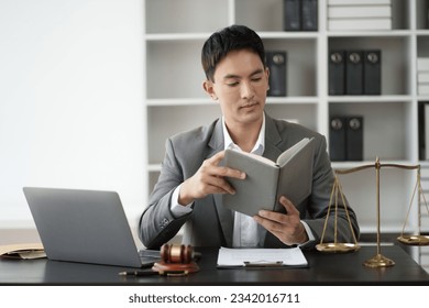 Asian professional lawyer reading books, studying about the case in his office room. - Powered by Shutterstock