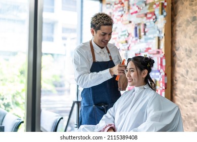 Asian Professional Male Hairdresser Use Scissors Cutting Woman's Hair. Attractive Hairstylist Giving Occupation Treatment Service, Combing Hair Of Caucasian Young Woman In Beauty Salon Or Barber Shop.