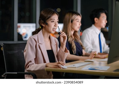 Asian professional successful female businesswomen assistant night shift call center helpline in formal business outfit and microphone headphones sitting smiling talking helping customers online. - Powered by Shutterstock