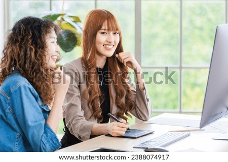 Asian professional successful young female businesswoman creative graphic designer in casual outfit sitting holding fists up celebrating job deal done acheivement with colleague pointing screen.