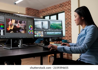 Asian Professional Video Editor Sitting At Multi Monitor Workspace While Enhancing Movie Footage Quality Using Advanced Software. Post Production House Team Leader Editing Film Frames.