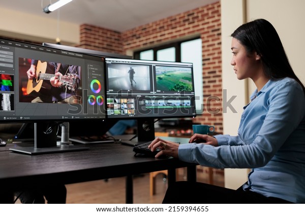 Asian
professional video editor sitting at multi monitor workspace while
enhancing movie footage quality using advanced software. Post
production house team leader editing film
frames.