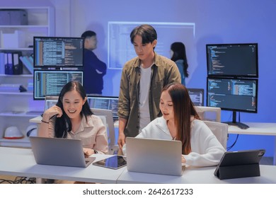 Asian programmers collaborating on software development at night, focused on writing code across multiple monitors in a tech office environment Programmers Collaborating on Software Development - Powered by Shutterstock - Get 15% off with code: PIKWIZARD15