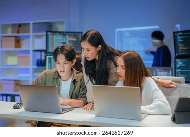 Asian programmers collaborating on software development at night, focused on writing code across multiple monitors in a tech office environment Programmers Collaborating on Software Development