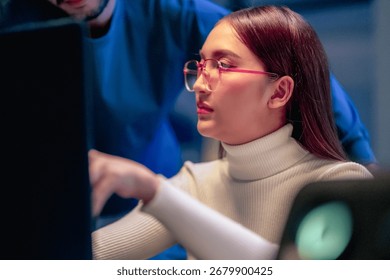 Asian programmers collaborating on software development at night, focused on writing code across multiple monitors in a tech office environment Programmers Collaborating on Software Development