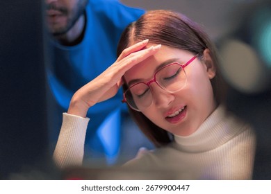 Asian programmers collaborating on software development at night, focused on writing code across multiple monitors in a tech office environment Programmers Collaborating on Software Development