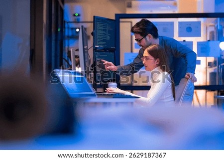 Asian programmers collaborating on software development at night, focused on writing code across multiple monitors in a tech office environment  Programmers Collaborating on Software Development 