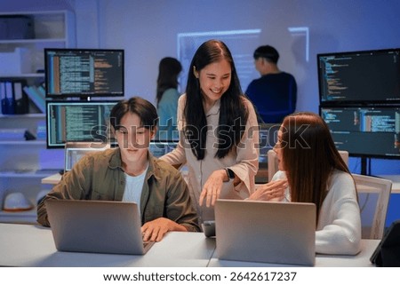Asian programmers collaborating on software development at night, focused on writing code across multiple monitors in a tech office environment Programmers Collaborating on Software Development