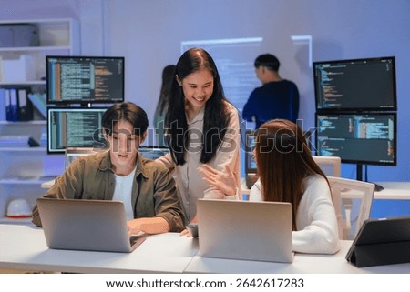Asian programmers collaborating on software development at night, focused on writing code across multiple monitors in a tech office environment Programmers Collaborating on Software Development