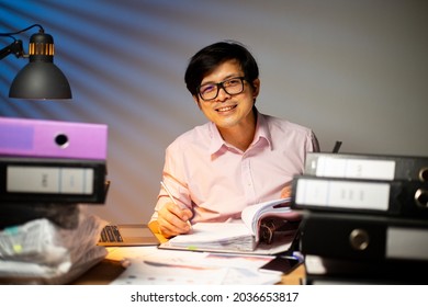 Asian Project Manager Smile And Happy With His Job.Occupation Overwork.Thai Freelancer Do Deadline Overtime Concept.Work Late At Night. 