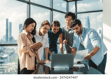 Asian project manager uses laptop displayed data analysis while professional business team brainstorming marketing idea at business meeting. Working together,sharing idea, planing strategy. Tracery.